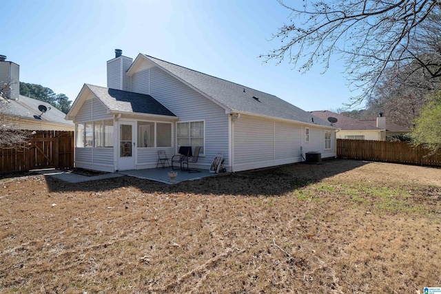 rear view of property featuring a patio, a sunroom, fence, a yard, and a shingled roof