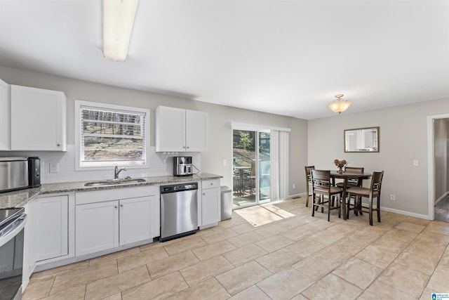 kitchen with a sink, white cabinetry, appliances with stainless steel finishes, decorative backsplash, and light stone countertops