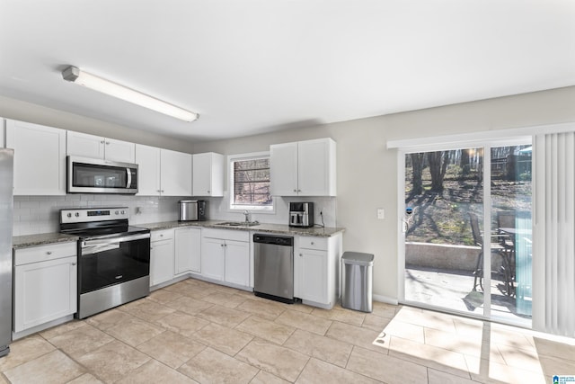 kitchen featuring backsplash, appliances with stainless steel finishes, stone countertops, white cabinetry, and a sink