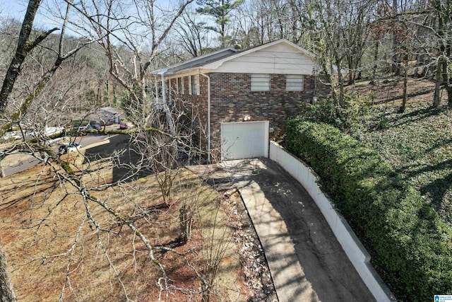 view of home's exterior featuring brick siding, driveway, and a garage