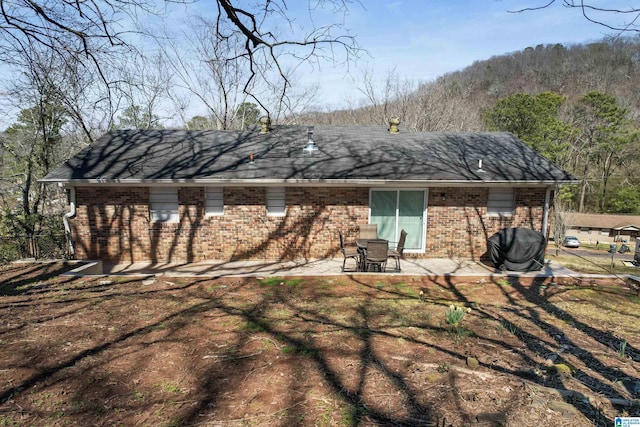 back of house with brick siding and a patio