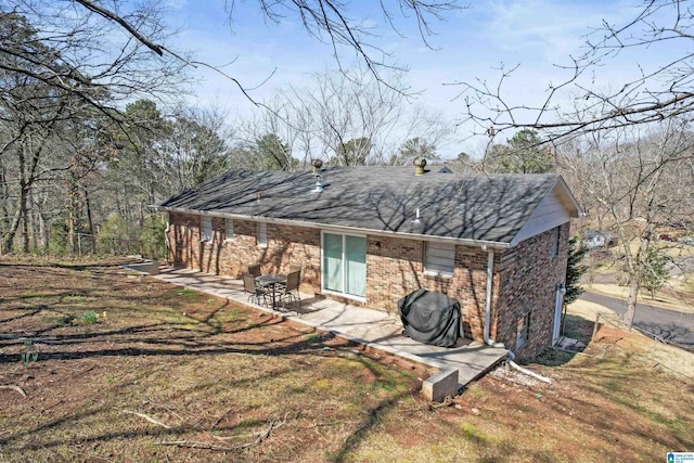 rear view of property featuring brick siding and a patio area