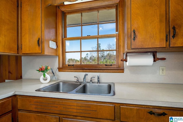 kitchen featuring brown cabinets, light countertops, and a sink