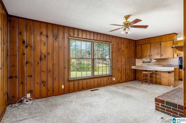 kitchen featuring carpet, visible vents, ceiling fan, light countertops, and brown cabinets