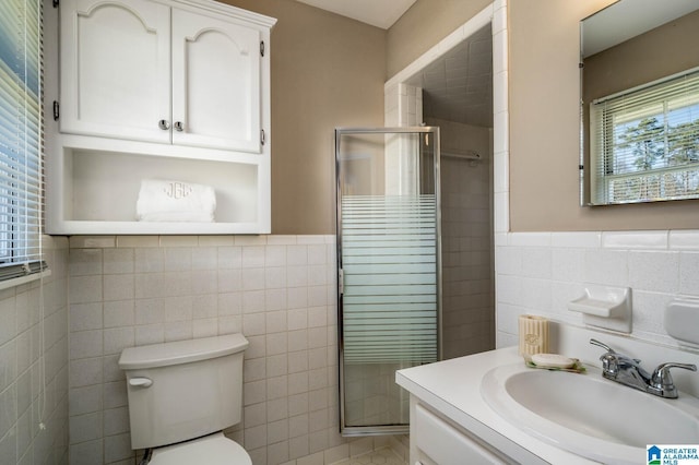 bathroom featuring toilet, a stall shower, tile walls, wainscoting, and vanity