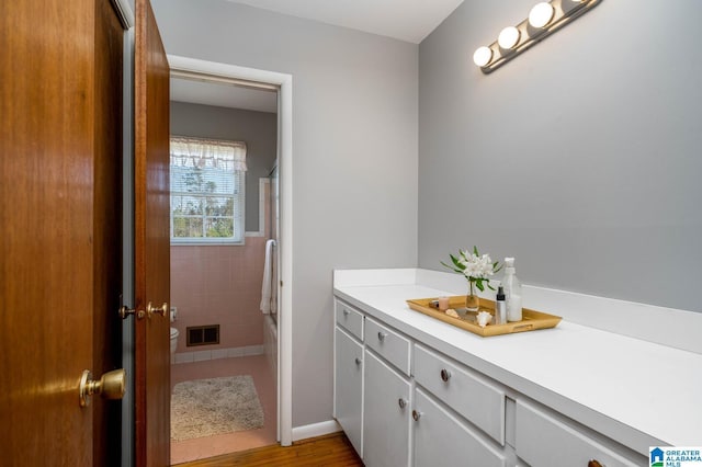 bathroom featuring tile walls, toilet, visible vents, and shower / bathtub combination