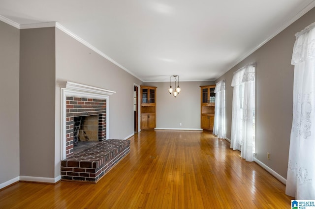 unfurnished living room featuring a chandelier, baseboards, wood-type flooring, and ornamental molding