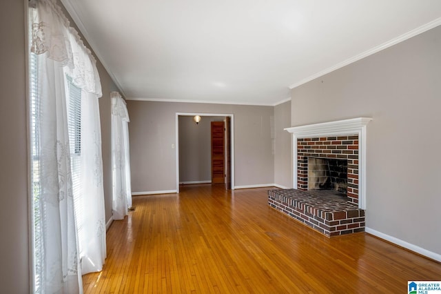 unfurnished living room with baseboards, a brick fireplace, crown molding, and hardwood / wood-style flooring