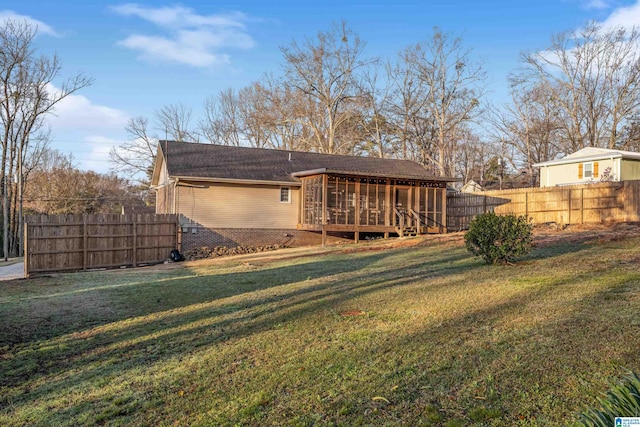 back of property with fence, a lawn, and a sunroom