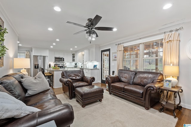 living area with light wood finished floors, recessed lighting, and ornamental molding