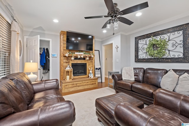 living area featuring a ceiling fan, wood finished floors, recessed lighting, a fireplace, and ornamental molding