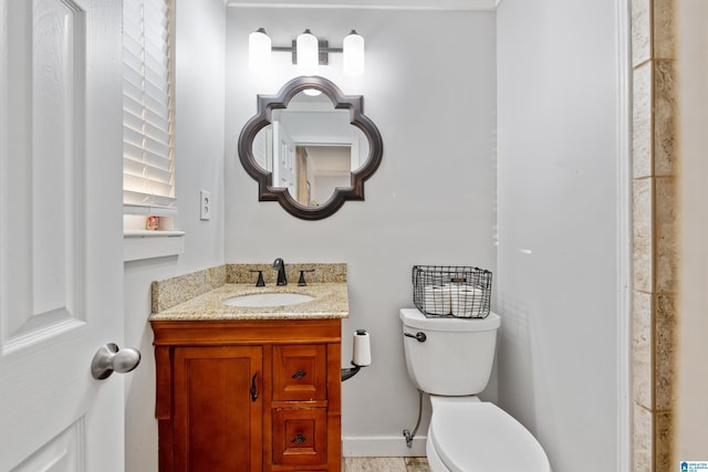 half bathroom featuring vanity, toilet, and baseboards