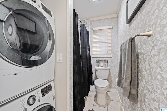 laundry area with tile patterned flooring, laundry area, wallpapered walls, and stacked washer and dryer