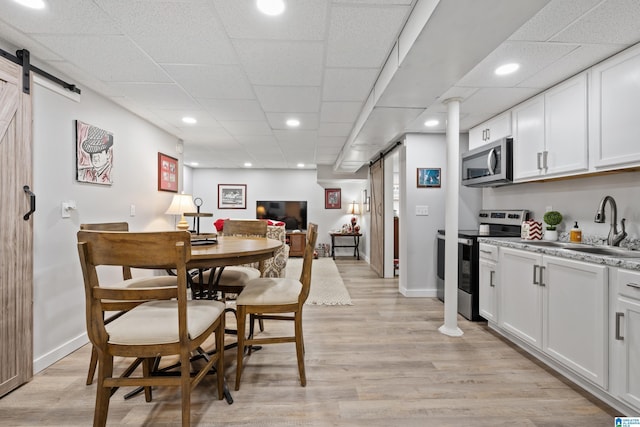 dining space featuring light wood-style flooring, baseboards, and a barn door