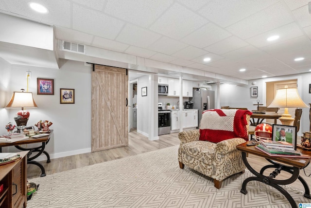 living area with visible vents, baseboards, recessed lighting, light wood-style floors, and a barn door