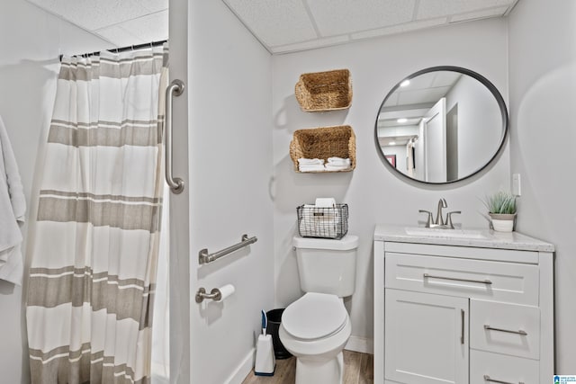 full bathroom with a drop ceiling, toilet, wood finished floors, and vanity