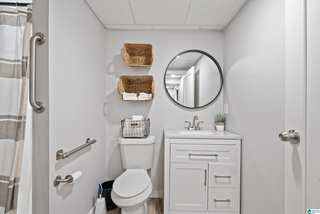 bathroom featuring baseboards, a paneled ceiling, toilet, and vanity