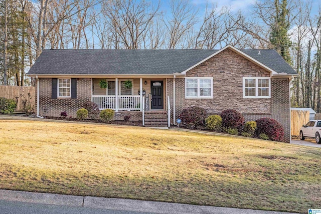 ranch-style home featuring stone siding, brick siding, covered porch, and a front yard