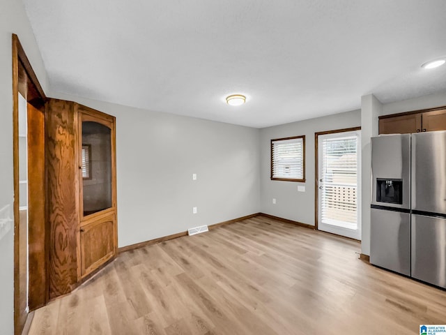 unfurnished living room with visible vents, baseboards, and light wood finished floors