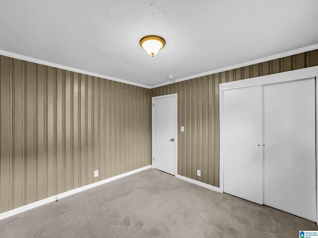 unfurnished bedroom with crown molding, a closet, carpet floors, and a textured ceiling