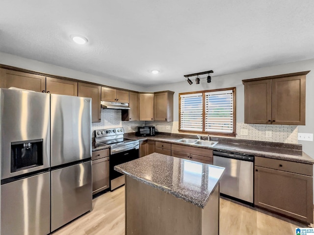 kitchen featuring decorative backsplash, appliances with stainless steel finishes, light wood-style floors, and a sink