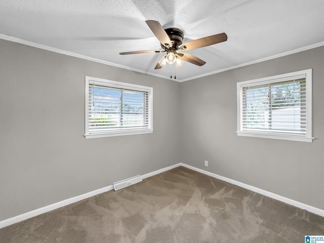 carpeted empty room featuring visible vents, baseboards, ceiling fan, and crown molding