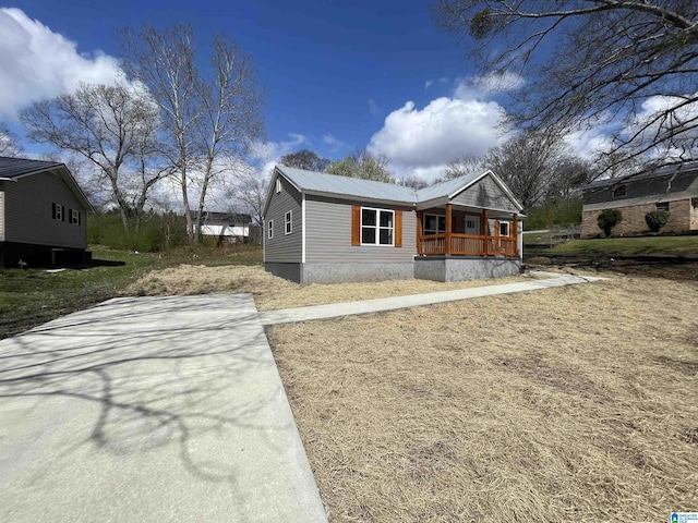 view of front of home with a porch, concrete driveway, and metal roof