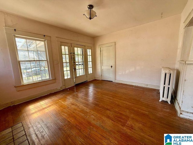 unfurnished room featuring baseboards, wood-type flooring, and radiator