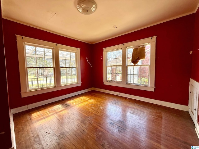 spare room featuring crown molding, baseboards, and hardwood / wood-style flooring