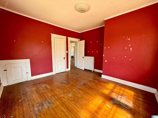 spare room featuring baseboards, radiator, crown molding, and hardwood / wood-style flooring