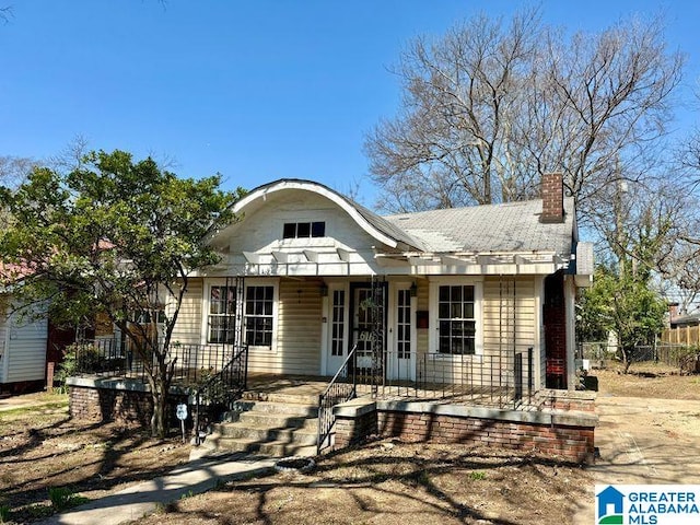 view of front facade featuring a porch and a chimney