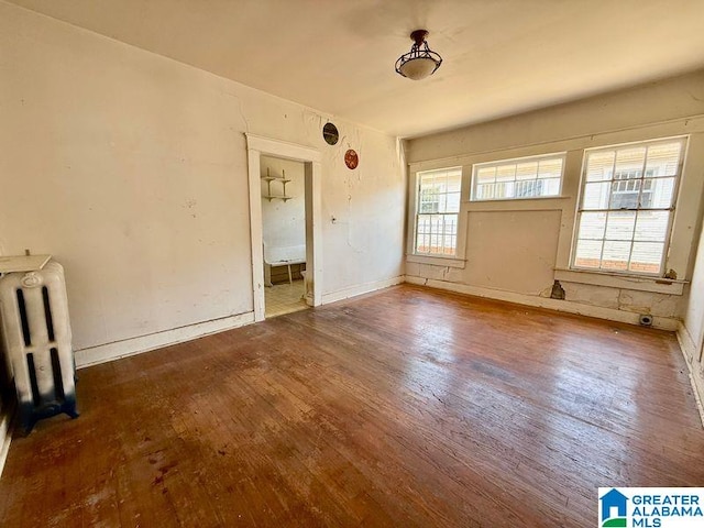 unfurnished room with radiator, baseboards, and hardwood / wood-style flooring