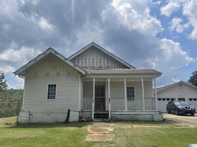 view of front facade with board and batten siding, a front yard, a garage, and covered porch