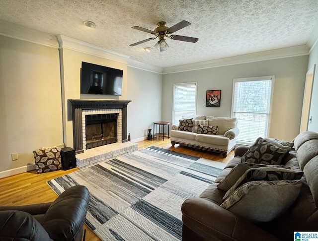living room featuring baseboards, wood finished floors, a fireplace, and ornamental molding