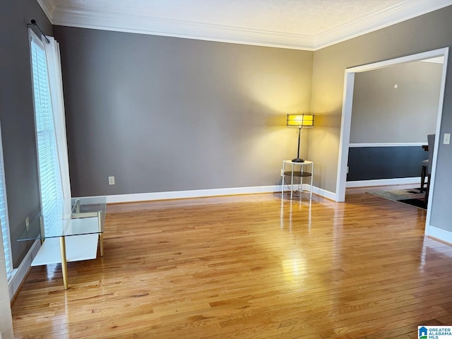 empty room with light wood-type flooring, baseboards, and ornamental molding
