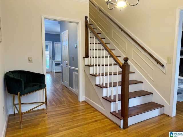 stairs featuring visible vents, baseboards, wood finished floors, and crown molding