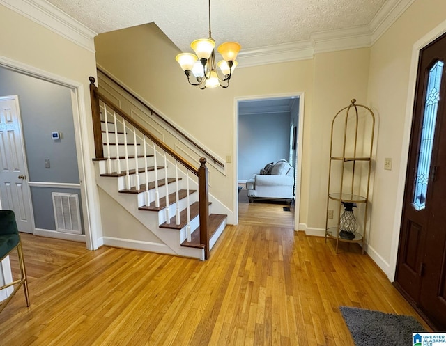 foyer entrance with light wood finished floors, visible vents, a chandelier, stairs, and a textured ceiling