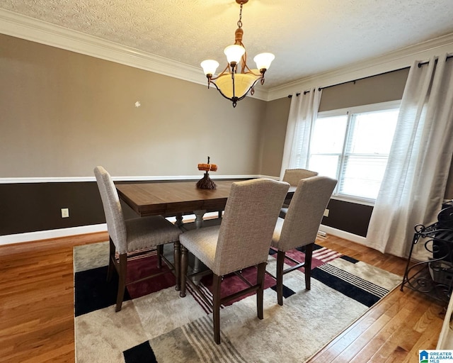 dining area with light wood-style floors, a chandelier, crown molding, and a textured ceiling