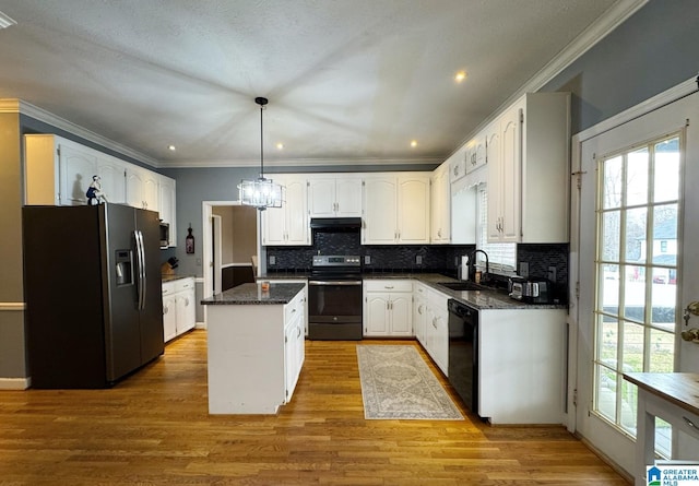 kitchen featuring a kitchen island, under cabinet range hood, white cabinets, stainless steel appliances, and a sink