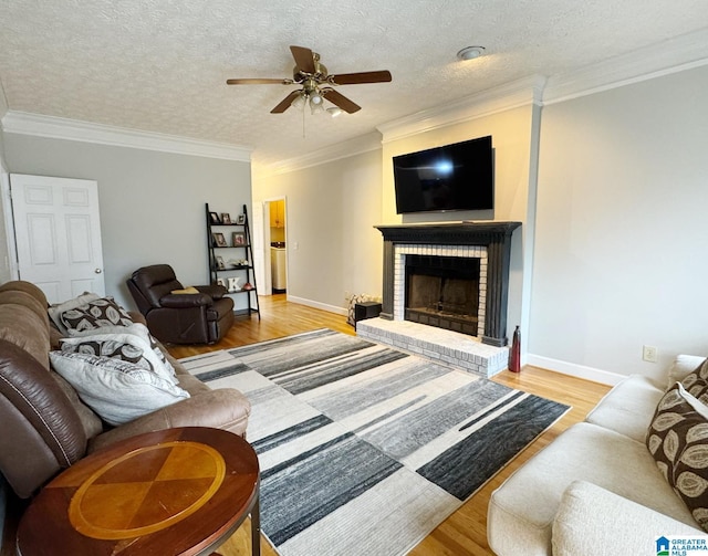 living room featuring baseboards, wood finished floors, a fireplace, and ornamental molding