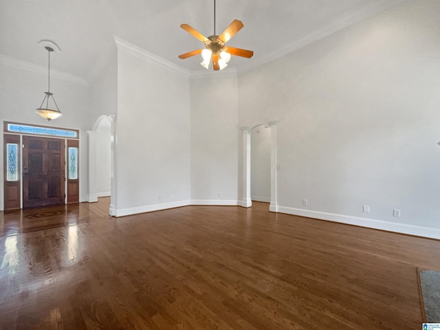 interior space featuring dark wood finished floors, crown molding, baseboards, and arched walkways