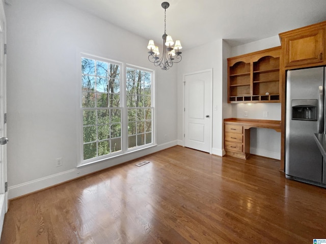 unfurnished dining area with wood finished floors, visible vents, and baseboards