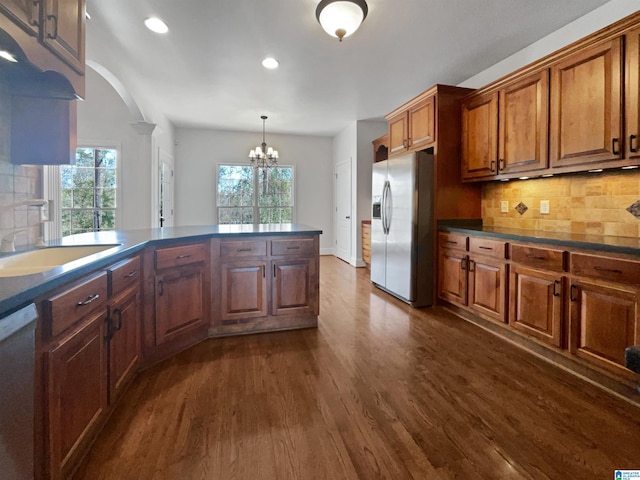 kitchen with a sink, dark countertops, stainless steel appliances, a healthy amount of sunlight, and dark wood-style flooring