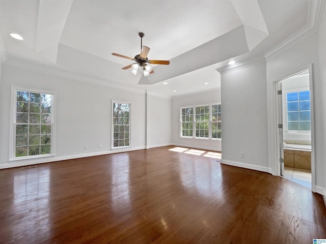 unfurnished room featuring a tray ceiling, baseboards, wood finished floors, and crown molding