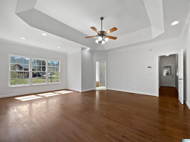 interior space with a tray ceiling, baseboards, wood finished floors, and ornamental molding