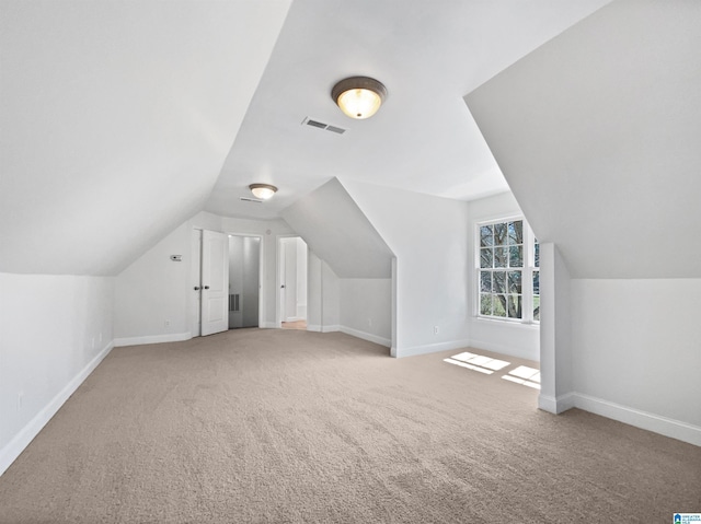 additional living space with visible vents, carpet flooring, baseboards, and vaulted ceiling