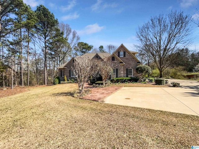 view of front of house featuring brick siding, a front lawn, and driveway