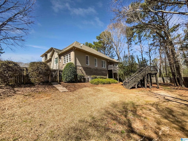 exterior space featuring stairway, brick siding, a deck, and fence