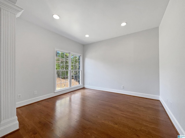 unfurnished room featuring recessed lighting, baseboards, dark wood-style flooring, and ornate columns