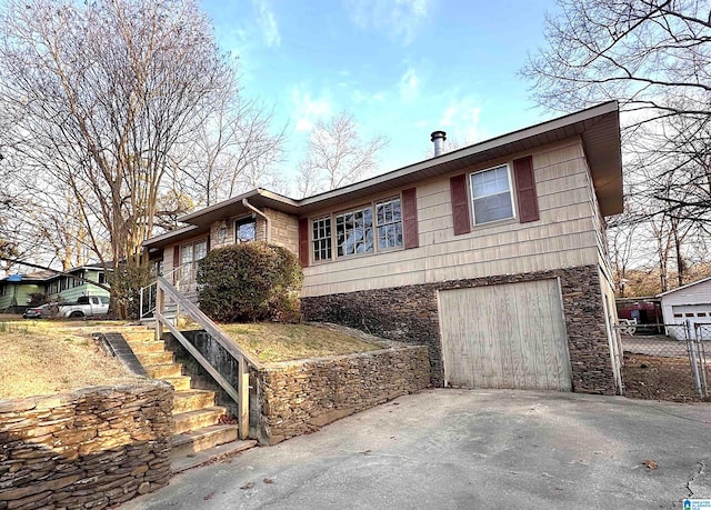 view of front of house with aphalt driveway, stone siding, an attached garage, and stairway